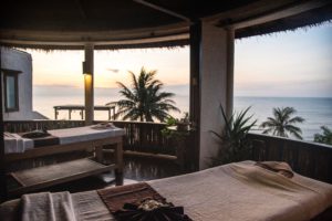 A massage table set-up on a covered deck overlooking a tropical view