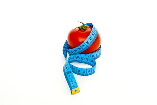 A red apple surrounded by a blue measuring tape. Eating healthy to bring your desired outcome.